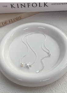 Détail du collier étoile de mer en argent S925 avec perle d'eau douce sur plat en céramique