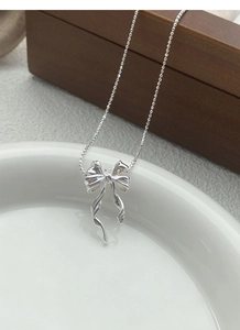 Détail du collier avec pendentif papillon en argent S925 sur un plateau en céramique