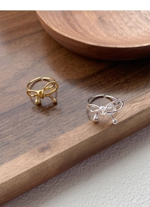 Detailed view of woven silver bow rings in gold and silver finishes with adjustable bands