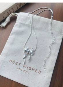 Détail du collier pendentif papillon argenté avec chaîne à billes sur emballage cadeau