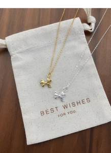 Detailansicht goldener und silberner Schleifenketten auf einem kleinen Stoffbeutel
