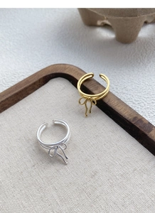 Detail showing gold and silver bow rings on a linen tray with elegant dual-band design
