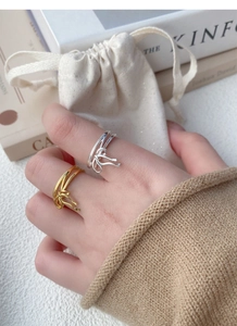 Detail of silver and gold bow rings on fingers with minimalist lifestyle backdrop
