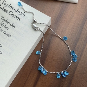 Elegant 925 silver beaded bracelet with blue teardrop zircons on a rustic wood background