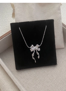 Vue macro d'un collier papillon en argent sur velours noir avec des détails élégants