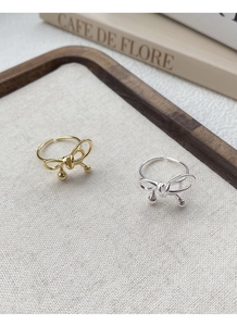 Detail of gold and silver S925 sterling silver bow rings with elegant metal bead accents