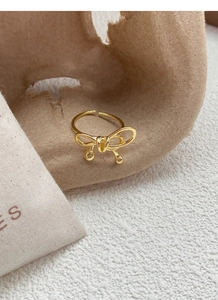 Detailed shot of golden bowknot ring with small round beads on textured background