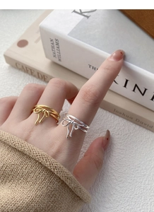 Detail of stacked bow rings in gold and silver finish with multi-layer line design