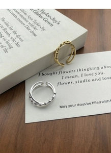 Detail of minimalist double-layered silver and gold bead rings on a wooden table