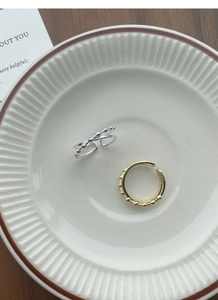 Close-up of gold and silver S925 sterling silver beaded rings on white ceramic plate