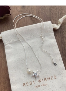 Détail du pendentif étoile de mer en argent S925 avec perle sur pochette cadeau blanche