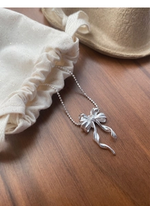 Détail du collier pendentif papillon en argent posé sur un élégant pochon cadeau en tissu