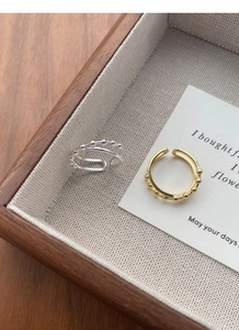 Close-up of adjustable double-layered silver and gold rings with delicate bead details