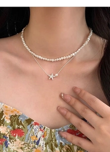 Gros plan du collier double épaisseur en argent S925 avec pendentif étoile de mer et perles