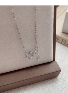 Macro shot of silver S925 necklace featuring a zircon flower pendant and butterfly detail