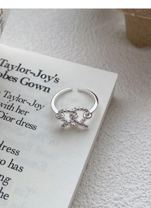 Macro shot of silver woven twist knot ring on an elegant minimalist book page background