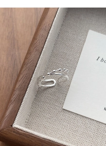 Detail of double-layer silver ring with round bead design on a wooden tray