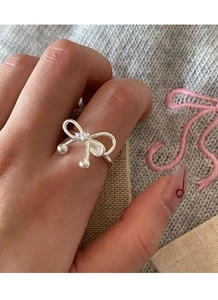Detail of S925 silver bow ring with hanging polished beads on a woven textured background