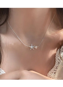 Gros plan du pendentif étoile de mer en argent S925 avec une perle d'eau douce au cou