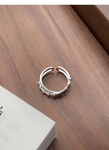 Detail of S925 sterling silver layered ring with beaded texture on dark wood surface
