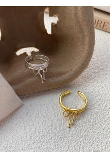 Detail view of silver and gold bow rings with elegant multi-layer metal wire design