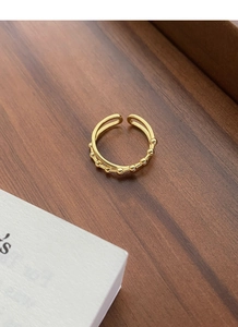 Detail of a minimalist gold double-layer open ring featuring bead texture on a wooden tray
