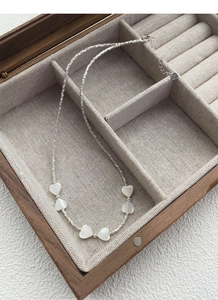 Détail macro de six pendentifs cœurs en nacre blanche sur une chaîne en argent S925