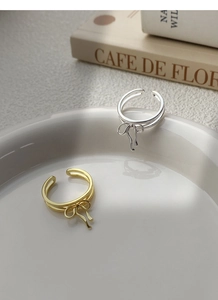 Detailed shot of gold and silver double-layered bow rings on a ceramic plate