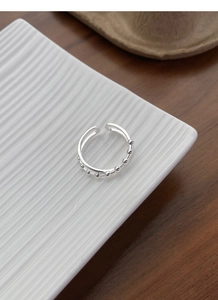 Detailed shot of S925 sterling silver double-layer open ring on a white ceramic plate