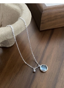 Macro detail of S925 sterling silver chain with light blue round gemstone pendant
