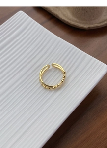 Macro detail of golden double-layer ring with delicate beads on white ceramic tray