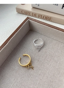 Detail of elegant gold and silver bow open rings displayed on a wooden tray