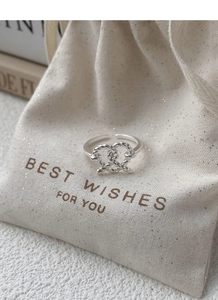 Macro shot of silver woven heart knot ring on a textured fabric gift pouch