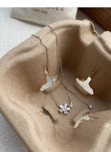 Macro detail of silver necklace with five-petal flower pendant on aesthetic background