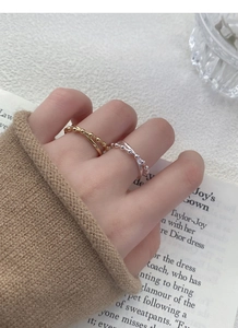 Close-up of gold and silver S925 beaded crossover rings worn by a model