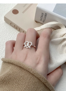 Detailed view of an S925 sterling silver braided knot heart ring worn on a finger