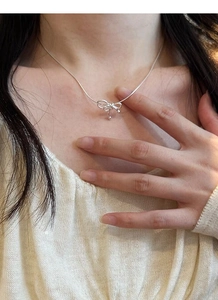 Gros plan du collier nœud en argent S925 avec breloques perles sur une chaîne serpent