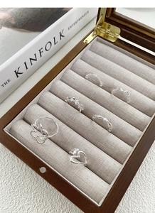 Macro view of several S925 sterling silver minimalist heart and knot rings set in a wood box