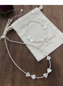 Gros plan détaillé du poinçon S925 sur le collier et le bracelet en nacre en forme de cœur
