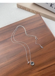 Detail of S925 sterling silver chain with a round blue stone pendant on a wood board