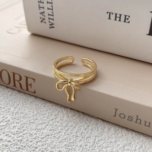 Elegant gold bow open ring featuring a triple-strand twisted band on vintage books