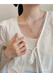 Detail of silver S925 pretzel bow necklace and ring set on model with lace top