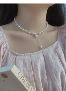 Dettaglio ravvicinato di una collana di perle barocche con ciondolo a cuore su una modella
