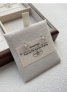 Close-up of S925 silver geometric pearl stud earrings on a linen display card