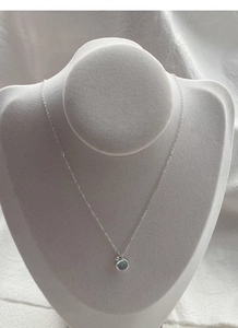 Detailed close-up of S925 sterling silver necklace with light blue round gemstone on a stand