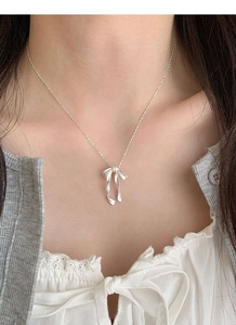 Gros plan d'un collier avec pendentif nœud en argent S925 porté au cou avec détails raffinés