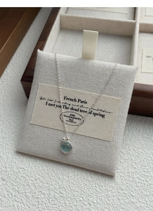 Detail of S925 silver necklace with a round sea blue gemstone in a wooden jewelry box