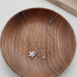 Elegant S925 sterling silver flower necklace with white zircon petals on wooden tray