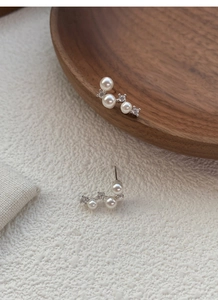 Close-up of S925 silver pearl stud earrings with sparkling rhinestones in an arc
