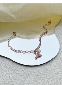 Détail du pendentif queue de poisson et perle sur une chaîne double en argent doré rose